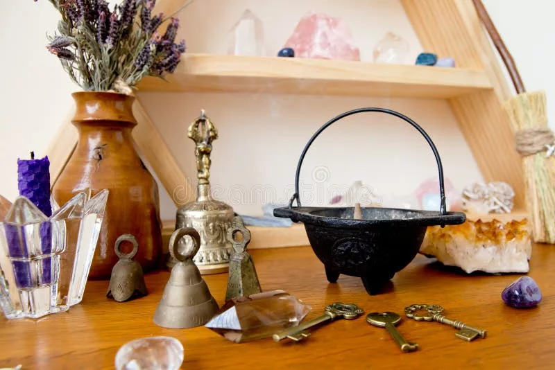 Mini cauldron on a witchcraft altar surrounded by crystals and herbs.